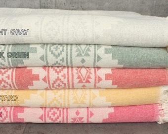 May include: Five Turkish towels stacked on top of each other. The towels are in the colors light gray, dark green, red, mustard yellow, and pink. Each towel has a geometric pattern.