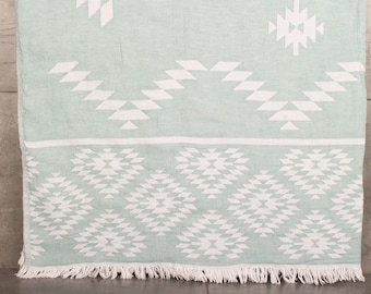 May include: A light green throw blanket with a white geometric pattern. The blanket has a fringe border.
