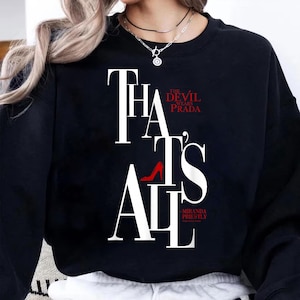 May include: Black sweatshirt with the text "THAT'S ALL" in white, with a red high heel shoe graphic. The words "THE DEVIL WEARS PRADA" are in red, and "-MIRANDA PRIESTLY" is in white.