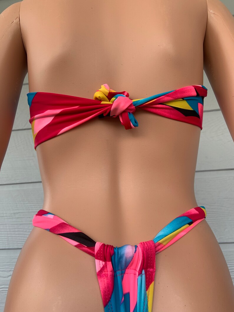 Pu&ograve; includere: Un top e un fondo bikini con stampa geometrica colorata e un design a nodo anteriore. La parte superiore &egrave; legata sul retro del collo e la parte inferiore &egrave; legata sui fianchi.