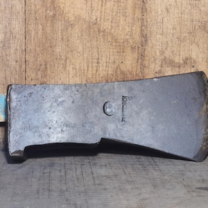 Peut inclure: Une tête de hache vintage à l'aspect sombre et vieilli. La tête en métal montre des signes d'âge et d'utilisation, avec une lame légèrement incurvée. La tête de hache porte l'inscription "FRANKSVILLE". Le fond est une surface en bois.