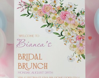 Può includere: Un cartello bianco su un cavalletto di legno, decorato con una composizione floreale di fiori rosa e bianchi. Il cartello recita "Benvenuti al Brunch Nuziale di Bianca" con la data e il luogo.