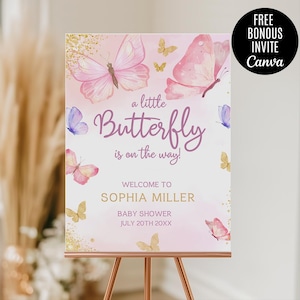 May include: A pink and gold baby shower welcome sign with butterflies and glitter. The text reads "a little Butterfly is on the way!"  "Welcome to Sophia Miller Baby Shower July 20th 20XX"