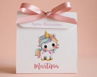May include: A white square favor box featuring a pink satin ribbon bow at the top. The box displays the text Santo Battesimo and the name Martina, with a colorful illustration of a unicorn adorned with flowers and a gold horn.