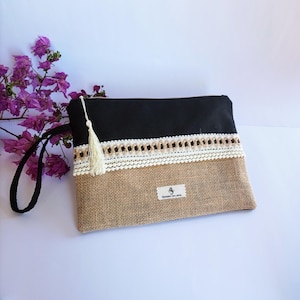 May include: A black and brown clutch bag with a white and brown lace trim. The bag has a small tassel and a label that says "Handmade with love".