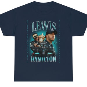 K&ouml;nnte beinhalten: Ein marineblaues T-Shirt mit einer Vintage-Grafik des Formel-1-Fahrers Lewis Hamilton. Die Grafik zeigt Hamilton in seinem Rennanzug, der eine Troph&auml;e h&auml;lt, mit dem Text "Lewis Hamilton" in fetter, wei&szlig;er Schrift. Der Text "7 Time World Drivers Champion" und "Mercedes-AMG Petronas" ist vertikal an den Seiten der Grafik gedruckt.