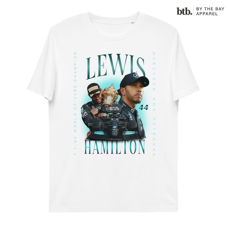 K&ouml;nnte beinhalten: Wei&szlig;es T-Shirt mit einem Grafikdruck von Lewis Hamilton, einem Formel-1-Fahrer, der eine Troph&auml;e h&auml;lt. Der Text "7 Time World Drivers Champion" und "Lewis Hamilton" ist auf dem Shirt aufgedruckt. Der Text "Mercedes-AMG Petronas" ist auf der rechten Seite des Shirts aufgedruckt.