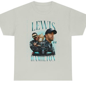 K&ouml;nnte beinhalten: Ein hellgraues T-Shirt mit einer Vintage-Grafik des Formel-1-Fahrers Lewis Hamilton, der eine Troph&auml;e h&auml;lt. Der Text "Lewis Hamilton" ist in blauer Schrift gedruckt.
