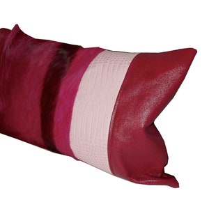 May include: A pink, red, and black decorative pillow with a textured, faux leather design.
