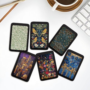 May include: A collection of six rectangular cardholders with various artistic designs. The designs include floral patterns, birds, and architectural scenes, all set against a black border. The cardholders are arranged on a white surface.