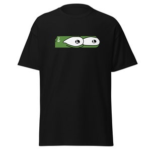 Puede incluir: Camiseta negra con una imagen de dibujos animados verde de dos ojos grandes con pupilas negras y escleróticas blancas.