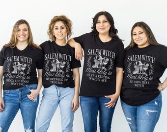 May include: Four women wearing black t-shirts with white text and graphics. The shirts say "Salem Witch" and have a witch and cauldron graphic. Each shirt has a different saying about being a witch.