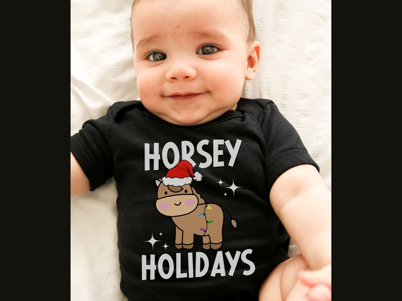 Peut inclure: Un b&eacute;b&eacute; portant un body noir avec un motif blanc repr&eacute;sentant un cheval brun portant un bonnet de P&egrave;re No&euml;l et le texte "HORSEY HOLIDAYS".