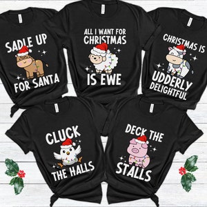 Peut inclure: Cinq t-shirts noirs avec des jeux de mots sur les animaux sur le th&egrave;me de No&euml;l. Les t-shirts pr&eacute;sentent une vache, un mouton, un poulet, un cochon et un cheval, chacun portant un chapeau de P&egrave;re No&euml;l et des lumi&egrave;res de No&euml;l. Le texte sur les t-shirts est : "Saddle Up For Santa", "All I Want For Christmas Is Ewe", "Christmas Is Udderly Delightful", "Cluck The Halls", et "Deck The Stalls".