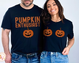 May include: A couple's matching t-shirts with a pumpkin theme. The man's shirt says "Pumpkin Enthusiast" and features a single winking pumpkin. The woman's shirt features two winking pumpkins.