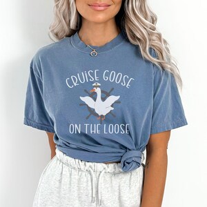 Puede incluir: Una camiseta azul con un ganso blanco que lleva un gorro de capit&aacute;n y el texto "Cruise Goose on the Loose".