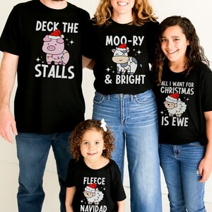 Peut inclure: Une famille de quatre personnes portant des t-shirts assortis sur le th&egrave;me de No&euml;l. Les t-shirts repr&eacute;sentent un cochon, une vache, un mouton et un mouton avec un chapeau de P&egrave;re No&euml;l. Le texte sur les t-shirts est "Deck the Stalls", "Moo-ry & Bright", "All I Want for Christmas is Ewe", et "Fleece Navidad".