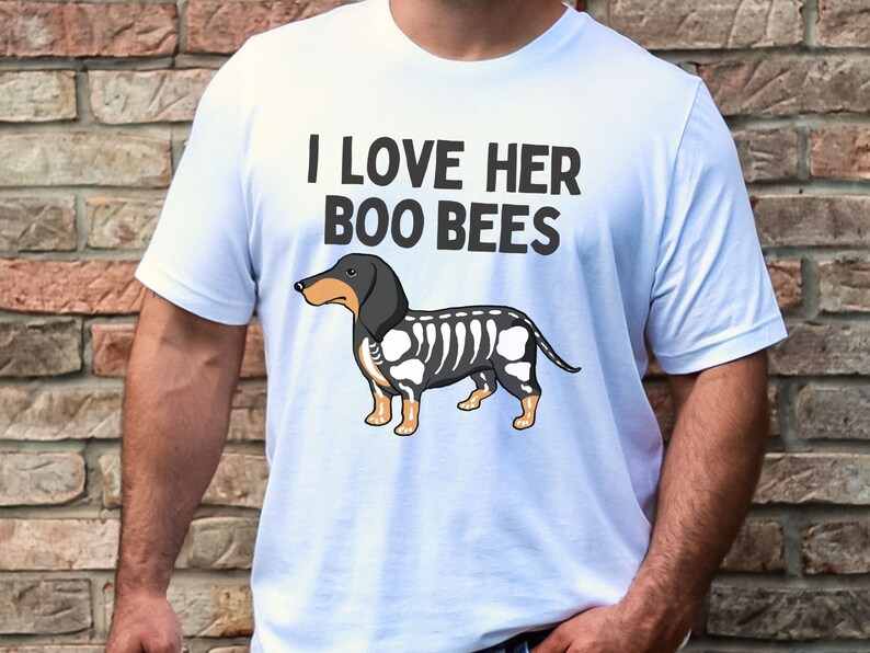 May include: White t-shirt with the text "I love her boo bees" and a cartoon image of a black and white dachshund with a skeleton design.