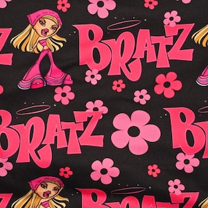 Pode incluir: Um tecido preto com um padrão repetido de flores cor-de-rosa, a palavra "Bratz" em cor-de-rosa e imagens de desenhos animados de bonecas com cabelo e roupas cor-de-rosa.