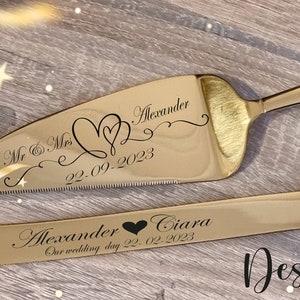 Può includere: Set di coltello e paletta per torte color oro. La paletta è incisa con "Mr & Mrs Alexander 22-09-2023" e un motivo a cuore. Il coltello è inciso con "Alexander Ciara Our wedding day 22-02-2023". Sono visibili anche le parole "Design 3".