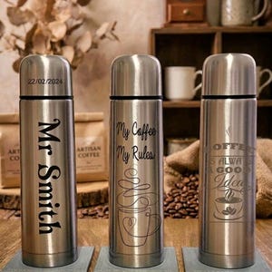 May include: Three stainless steel coffee flasks with black text and designs. One flask reads "Mr Smith" with the date "22/02/2024". The second reads "My Coffee My Rules" with a coffee cup design. The third reads "Coffee is always a good idea" with a coffee cup design.