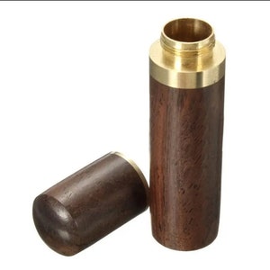 May include: A cylindrical wooden container with a brass top and bottom, and a separate, matching lid. The wood has a rich, dark brown color, and the brass has a golden hue. The lid is lying next to the container.
