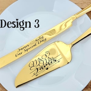 May include: Gold-colored cake knife and server set. The knife is engraved with "James & Kety, Our Special Day." The server is engraved with "Mr & Mrs James, EST 2022." The set is displayed on a white plate.