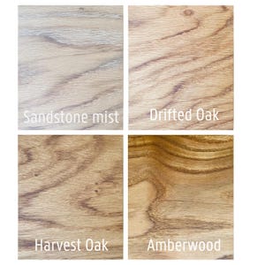 May include: Four wood samples showcasing different finishes: Sandstone Mist, Drifted Oak, Harvest Oak, and Amberwood. Each sample displays the natural grain and color variations of the wood, with text labels identifying each finish. The image is well-lit, highlighting the textures.