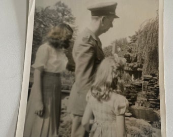 Man in military uniform with two girls standing before fountain