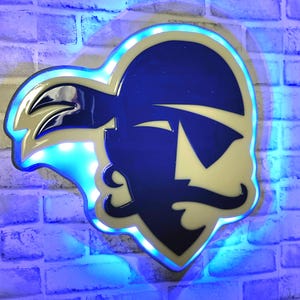 May include: A blue and white metal wall sign with a pirate head design. The sign is lit up with blue LED lights.