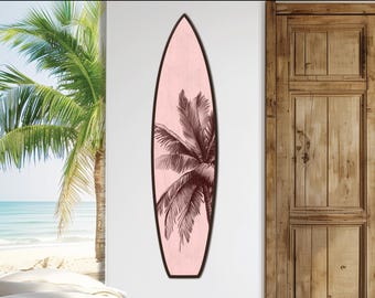 Könnte beinhalten: Ein pinkfarbenes Surfbrett mit einer schwarz-weißen Illustration einer Palme. Das Surfbrett hängt an einer weißen Wand.