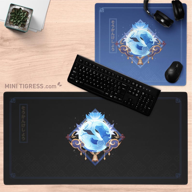 May include: Two mouse pads, one blue and one black, with a stylized design of two foxes in a circle. The design includes a lotus flower, clouds, and a bell. A black keyboard, mouse, and headphones are also present.
