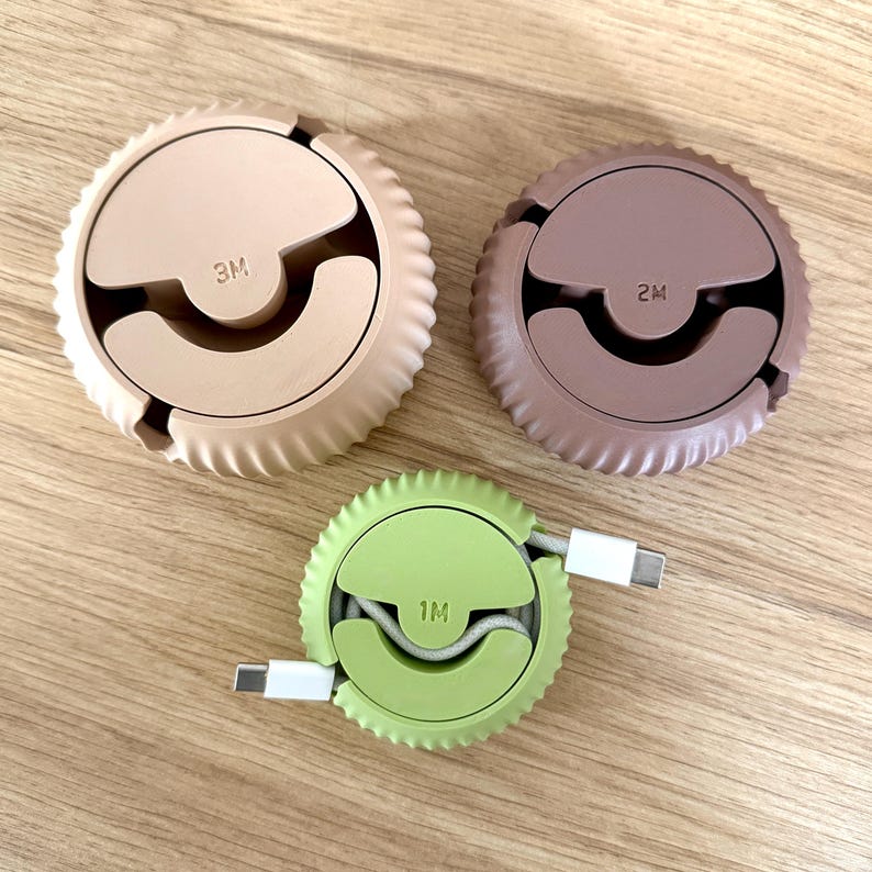 Photo of the bottom of the three sized cable organisers, one of them with a cable, showing the mechanism where the cable is inserted.