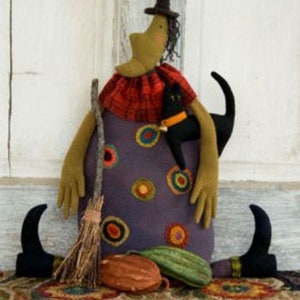 May include: A handmade witch doll with a purple and orange polka dot dress, a black cat, a broom, and a pumpkin. The doll is wearing a black hat and has a green face.