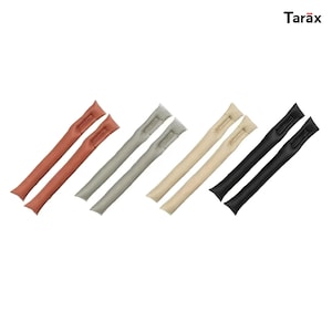 Pode incluir: Oito hastes de modelagem de cabelo longas, finas e flexíveis, dispostas em quatro pares de cores diferentes: terracota, verde sálvia, bege e preto. Cada haste apresenta uma superfície lisa com textura mate e uma pequena abertura de fenda perto do topo. O nome da marca Tarax está impresso em preto no canto superior direito.