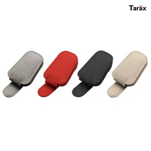 May include: Four rectangular magnetic clips with a textured surface, each featuring a small tab at the bottom. The clips are coloured light grey, red, black, and beige. The brand name Tarax is printed in the upper right corner of the image.