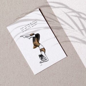 May include: A white card featuring a yoga illustration. The artwork shows a person in a handstand, wearing black and gold patterned clothing. The card has the text: "Stop acting so small. You are the universe in ecstatic motion."