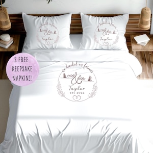 Può includere: Set di biancheria da letto bianco con due federe e un copripiumino. Ogni federa e il copripiumino presentano il testo "We decided on forever" e il nome "Taylor". Il design include una corona floreale e il testo "Est 2022".