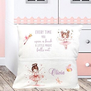 Op de afbeelding: Wit kussen met een zak, met illustraties van een ballerina, een toverstaf en vlinders. De tekst luidt: "Elke keer als je een boek opent, valt er een beetje magie uit." De naam "Olivia" wordt ook weergegeven.