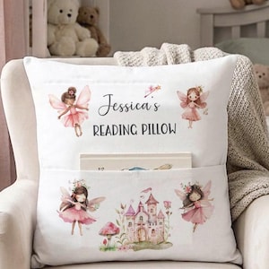Könnte beinhalten: Weißes Lesekissen mit Tasche, mit dem Text "Jessica's READING PILLOW". Das Kissen ist mit Aquarellillustrationen von Feen, einem Schloss und einem Pilz verziert. Ein Buch ist in der Tasche sichtbar.