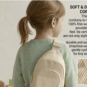 Puede incluir: Una bandolera de pana beige claro con un bolsillo frontal y una correa ajustable. La bolsa la lleva un ni&ntilde;o que lleva un su&eacute;ter verde claro. El texto de la imagen dice "SOFT & DURABLE CORDUROY".