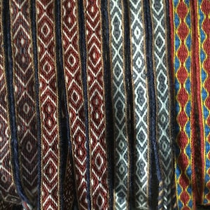 May include: A collection of woven fabric strips in various colors and patterns, including red, blue, white, and yellow. The strips have a geometric diamond pattern.