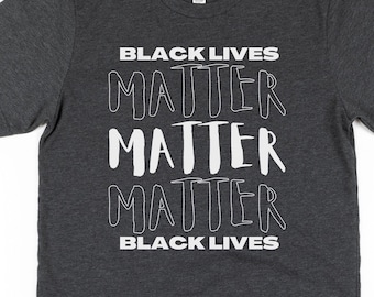 May include: Dark gray t-shirt with the text "Black Lives Matter" repeated four times in white, with the words "Matter" stylized in a handwritten font.