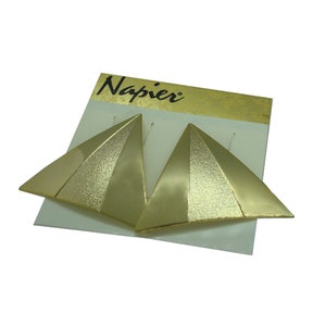 May include: A pair of gold-tone triangular earrings with a textured finish. The earrings are on a white card with the word "Napier" printed in black.