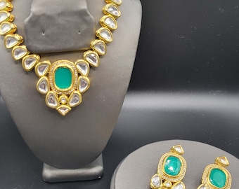 Peut inclure: Un collier et des boucles d'oreilles en or avec un pendentif en pierre précieuse verte et des boucles d'oreilles assorties. Le collier est composé de petites pierres en forme de larme.