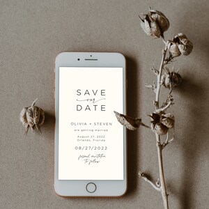 May include: A smartphone screen displaying a save the date announcement for Olivia and Steven's wedding on August 27, 2022 in Orlando, Florida. The text reads "Save our Date" with a handwritten flourish under "our". The date is displayed as 08/27/2022 and the text "formal invitation to follow" is written in cursive.