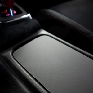 Peut inclure: Gros plan sur l'int&eacute;rieur d'une voiture noire avec un compartiment de rangement rectangulaire gris textur&eacute;.