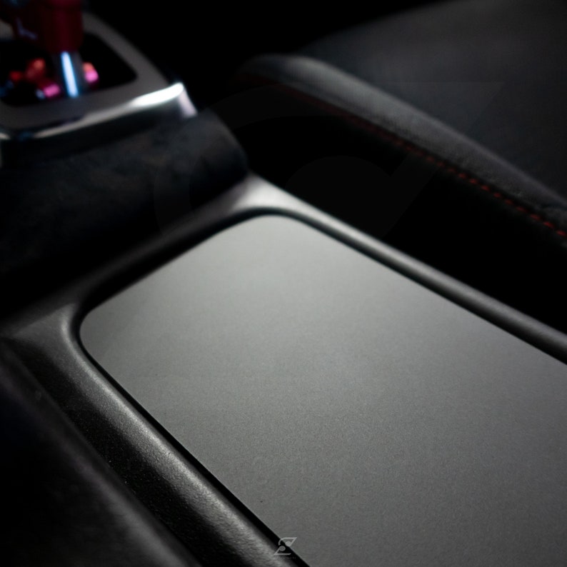 Peut inclure: Gros plan sur l'int&eacute;rieur d'une voiture noire avec un compartiment de rangement rectangulaire gris textur&eacute;.