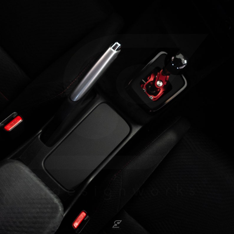 Peut inclure: Gros plan sur l'int&eacute;rieur d'une voiture, montrant un si&egrave;ge en cuir noir, un levier de frein &agrave; main argent&eacute; et un pommeau de levier de vitesse rouge apr&egrave;s-vente.