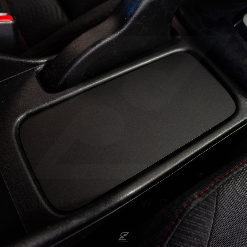 Peut inclure: Int&eacute;rieur de voiture noir avec une console centrale en cuir noir et un accoudoir &agrave; surpiq&ucirc;res rouges.